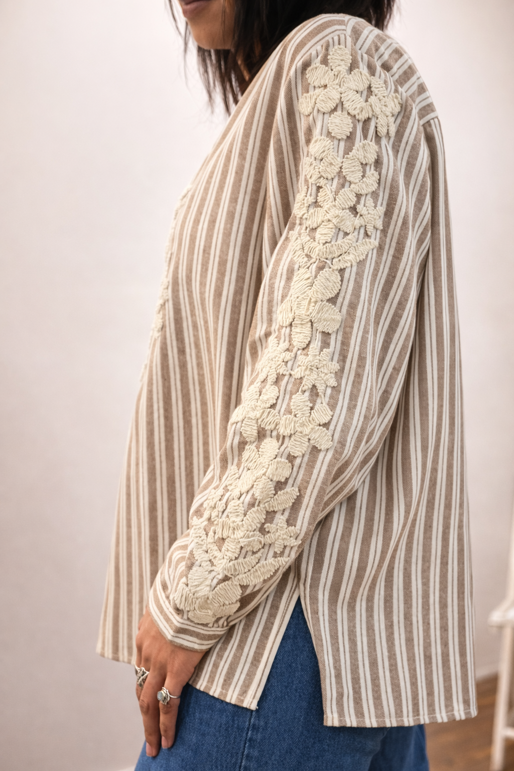 Blous_e STACEY rayée beige et écrue avec broderie florale écrue sur le devant et les manches, portée par une femme.